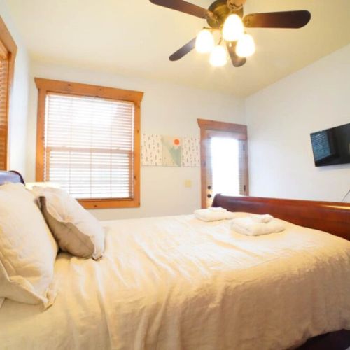 Bedroom #2 has a comfy queen bed, a wall-mounted TV, and access to a balcony shared with Bedroom #3.