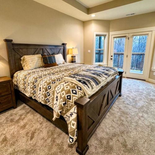 The primary bedroom features a king bed, a large en suite bathroom, a walk-in closet, and direct access to the back deck.