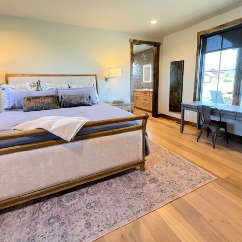The primary bedroom features a king bed, a dedicated workspace, a smart TV with a soundbar, and an expansive en suite bathroom.