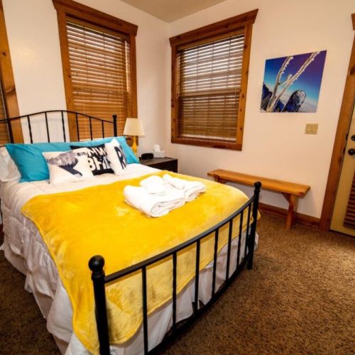 Bedroom #2 has a comfy queen bed, a wall-mounted TV, and access to a porch shared with Bedroom #3.
