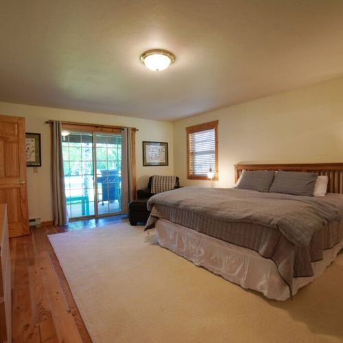 The spacious master bedroom has a king bed, a large closet, a TV, its own entrance to the front porch, and an en suite bathroom.