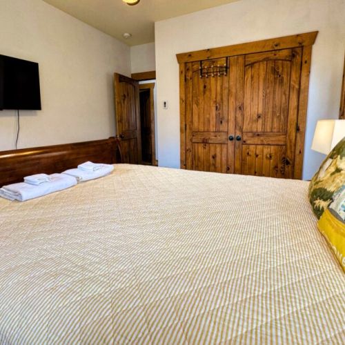 Bedroom #2 has a comfy queen bed, a wall-mounted TV, and access to a balcony shared with Bedroom #3.