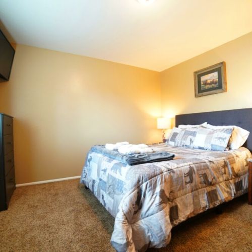 The master bedroom enjoys a queen bed and its own TV, as well as a dresser and a large closet.