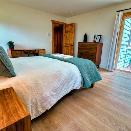 The primary bedroom features a queen bed, walk-in closet, large desk, direct access to the backyard, and a beautiful en suite bathroom.