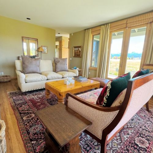 The sitting room enjoys gorgeous views of the mountains through its many windows, as well as plush seating options.