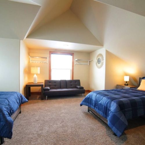 This upstairs bedroom has 2 twin beds, a sleeper sofa, and a large TV — a perfect getaway from the common area!