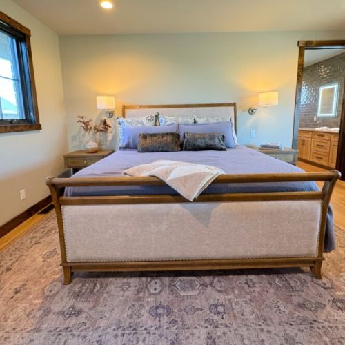 The primary bedroom features a king bed, a dedicated workspace, a smart TV with a soundbar, and an expansive en suite bathroom.