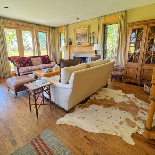 The sitting room enjoys gorgeous views of the mountains through its many windows, as well as plush seating options.