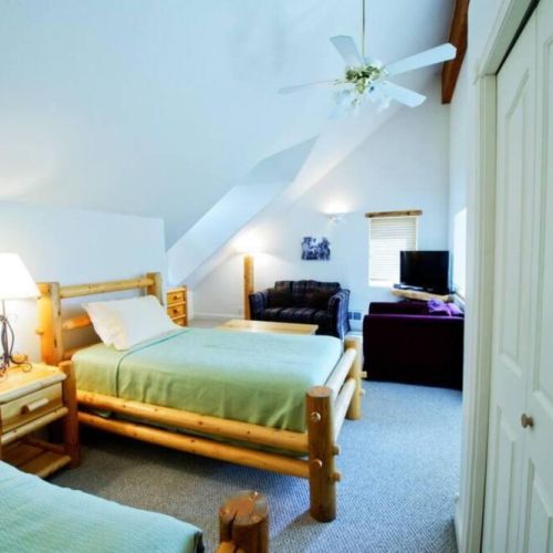 The third floor loft room features high ceilings and a cozy living area, as well as two twin bedrooms and an attached bathroom.