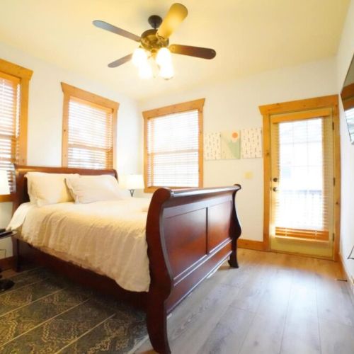 Bedroom #2 has a comfy queen bed, a wall-mounted TV, and access to a balcony shared with Bedroom #3.