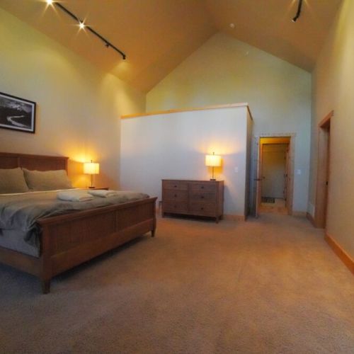 The master bedroom (located on the main level) features a king bed, a walk-in closet, access to the back deck, and an en suite bathroom with a soaking tub and shower.