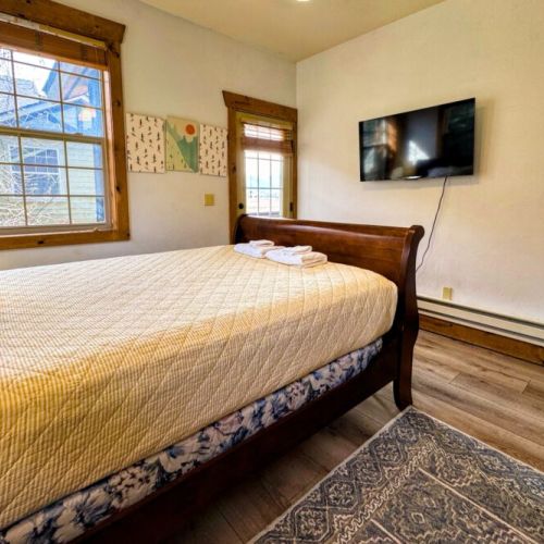 Bedroom #2 has a comfy queen bed, a wall-mounted TV, and access to a balcony shared with Bedroom #3.