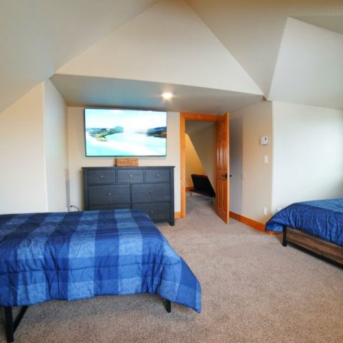 This upstairs bedroom has 2 twin beds, a sleeper sofa, and a large TV — a perfect getaway from the common area!