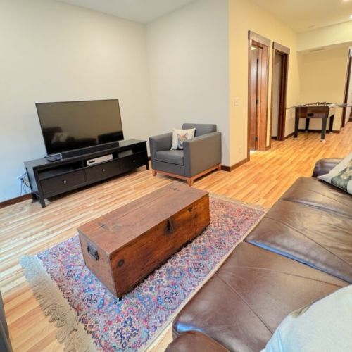 The basement living area features an array of comfortable seating as well as a smart TV.