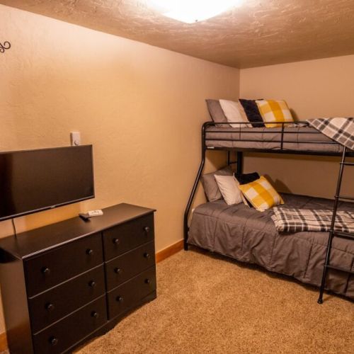 Down in the basement, bedroom #3 enjoys a twin-over-full bunk bed and an attached half-bath, as well as a TV — perfect for kids!