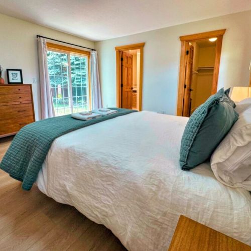The primary bedroom features a queen bed, walk-in closet, large desk, direct access to the backyard, and a beautiful en suite bathroom.