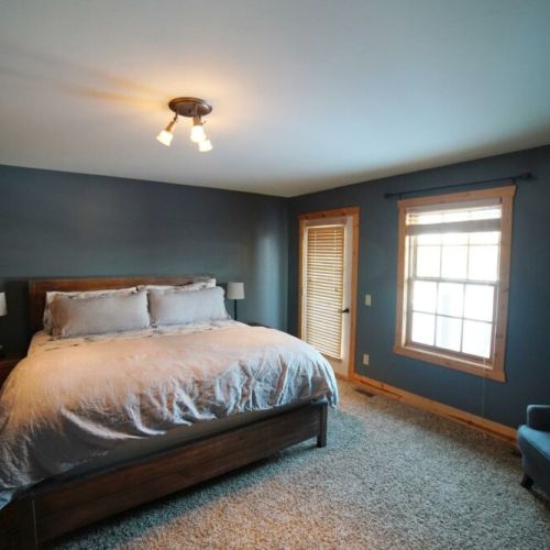 The master bedroom has a comfy king-sized bed with all-cotton bedding, an en suite bathroom, and a door out to the backyard.