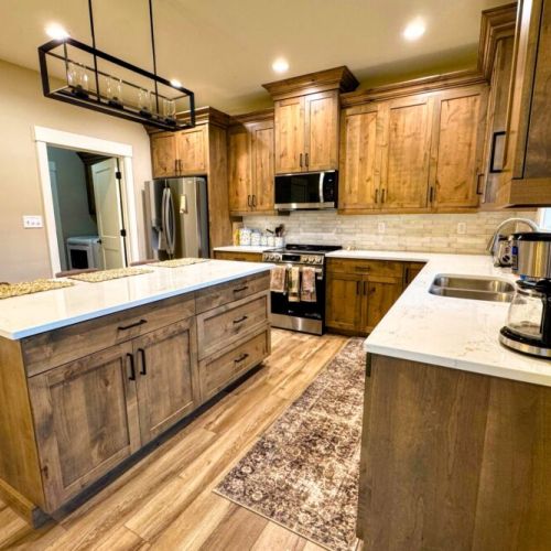 The fully equipped kitchen features custom wood cabinetry, stainless steel appliances, and a large island perfect for gathering.