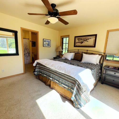 The master bedroom features a king bed, direct access to the back porch, a TV, and an en suite bath.