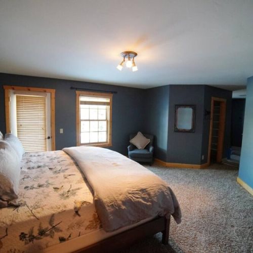 The master bedroom has a comfy king-sized bed with all-cotton bedding, an en suite bathroom, and a door out to the backyard.