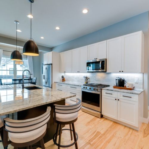 The fully equipped kitchen features sleek cabinetry, stainless steel appliances, and a large island perfect for gathering.