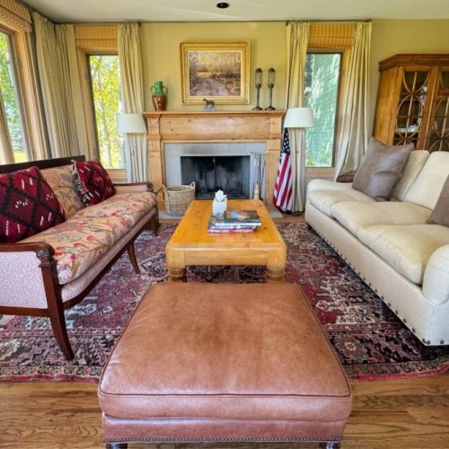 The sitting room enjoys gorgeous views of the mountains through its many windows, as well as plush seating options.