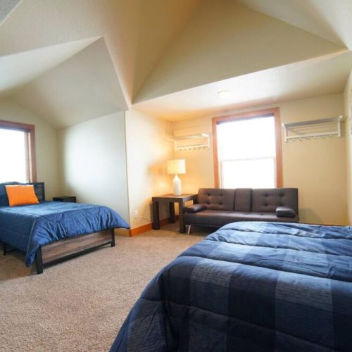 This upstairs bedroom has 2 twin beds, a sleeper sofa, and a large TV — a perfect getaway from the common area!