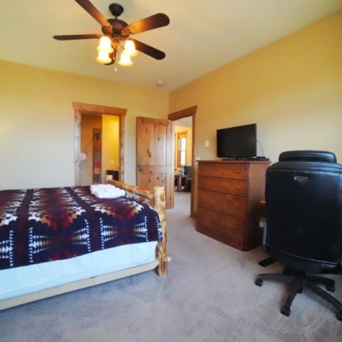 The master bedroom enjoys a king bed, an en suite bath, its own TV, and a sit-stand desk.