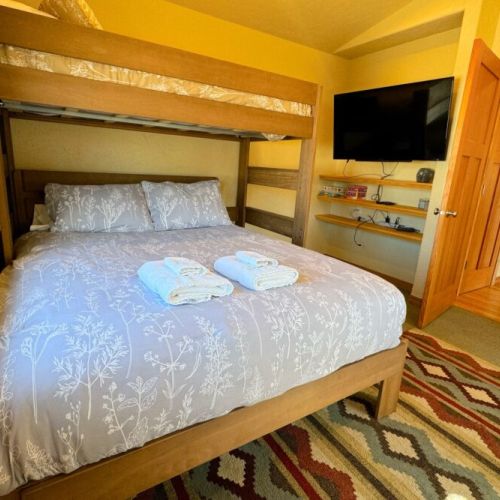 The downstairs bedroom features a twin-over-queen bunk bed, a closet, and a TV.