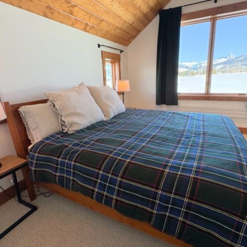 The primary bedroom (located upstairs) features a king bed, a walk-in closet, an en suite bathroom, and a direct view of the Tetons.