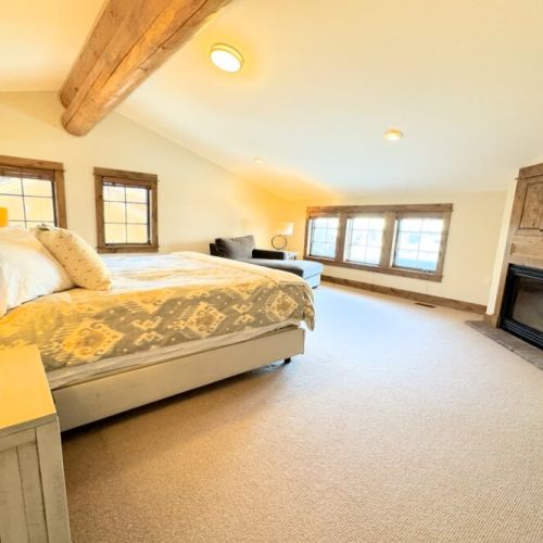 The primary bedroom (located on the top floor) features a king bed, gas fireplace, TV, and a large en suite bathroom with a shower/tub.
