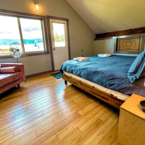 The upstairs bedroom has a king bed, closet space, and a comfy seat for lounging. This bedroom communicates through a small window to the living space on the first floor for heat conduction purposes.