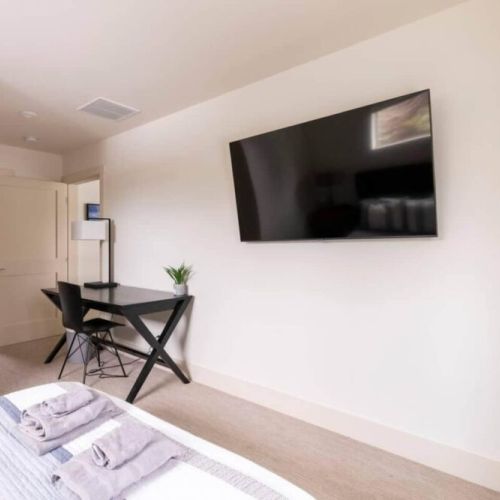 The master bedroom comes with a queen bed, a full en suite bath, and a lovely desk for reading or work. There is also a wall-mounted smart TV!