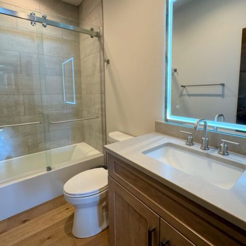The shared bathroom has a large tub/shower combo and a lighted mirror.