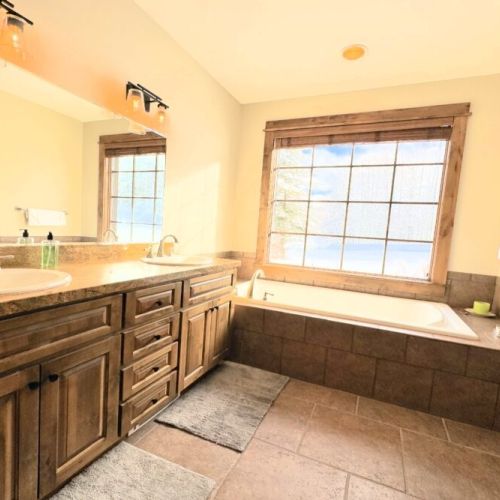 Bedroom #4 has its own bathroom on the lower level, complete with a double vanity, a huge tub, and a walk-in shower.