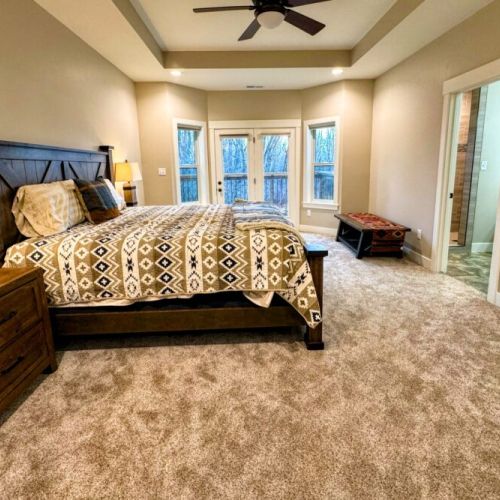 The primary bedroom features a king bed, a large en suite bathroom, a walk-in closet, and direct access to the back deck.
