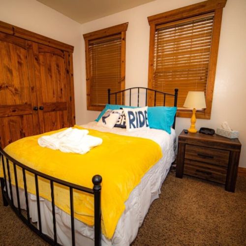 Bedroom #2 has a comfy queen bed, a wall-mounted TV, and access to a porch shared with Bedroom #3.