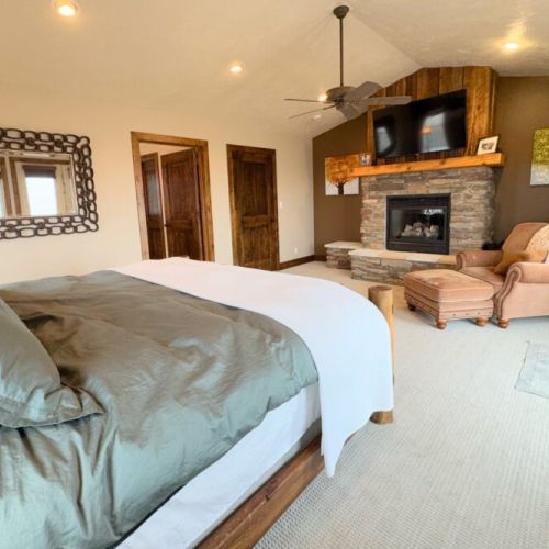 The primary bedroom features a king bed, a gas fireplace, a smart TV with a soundbar, a large en suite bathroom, and access to a private hot tub.