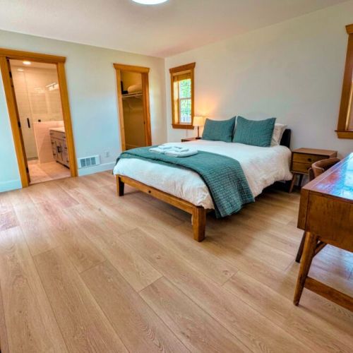 The primary bedroom features a queen bed, walk-in closet, large desk, direct access to the backyard, and a beautiful en suite bathroom.