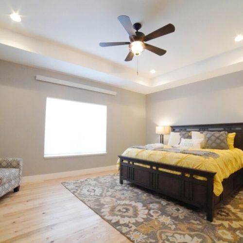 The spacious master bedroom enjoys a king bed, a chest of drawers, a couple lounge chairs, and an en suite bathroom.