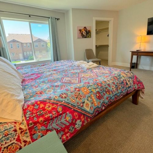 The spacious primary bedroom enjoys a king bed, a large walk-in closet, a flat-screen TV, and an en suite bathroom.