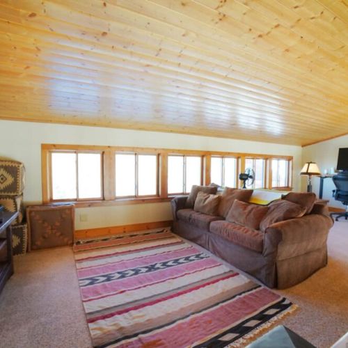 Above the main living room is a TV room, as well as a work station with a computer monitor.