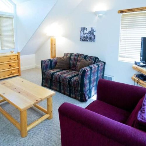 The third floor loft room features high ceilings and a cozy living area, as well as two twin bedrooms and an attached bathroom.