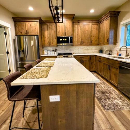 The fully equipped kitchen features custom wood cabinetry, stainless steel appliances, and a large island perfect for gathering.