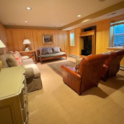 The basement enjoys another living area complete with two sofas, comfortable sitting chairs, and a TV.