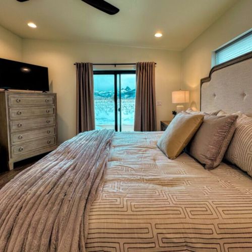 The primary bedroom features a king bed, views of the Tetons, a smart TV, and an expansive en suite bathroom.