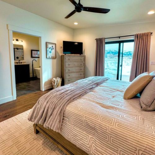 The primary bedroom features a king bed, views of the Tetons, a smart TV, and an expansive en suite bathroom.
