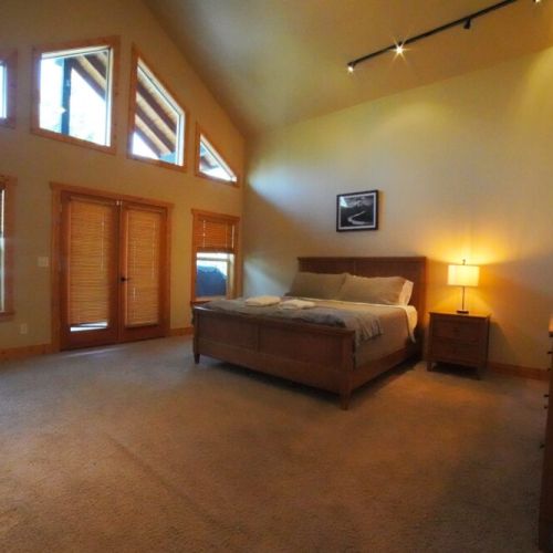 The master bedroom (located on the main level) features a king bed, a walk-in closet, access to the back deck, and an en suite bathroom with a soaking tub and shower.