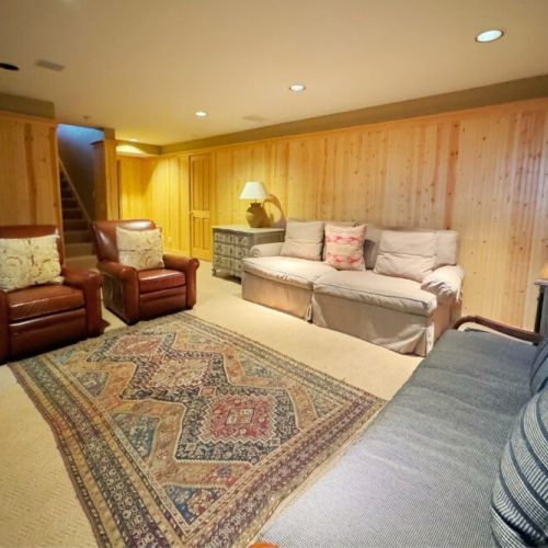 The basement enjoys another living area complete with two sofas, comfortable sitting chairs, and a TV.