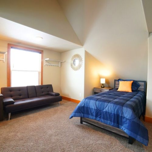 This upstairs bedroom has 2 twin beds, a sleeper sofa, and a large TV — a perfect getaway from the common area!